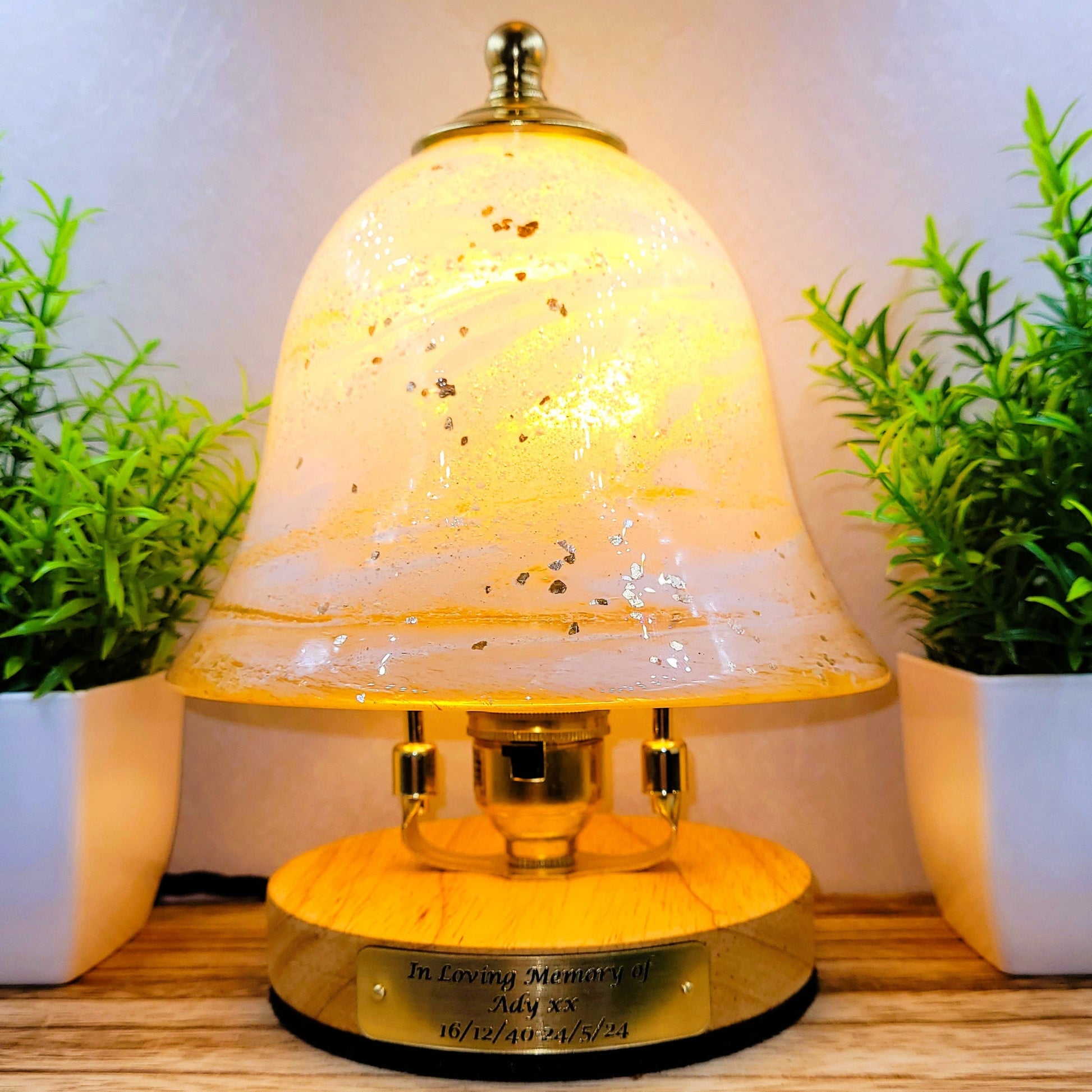 Decorative lamp with a glass cover on a wooden surface with plants in the background