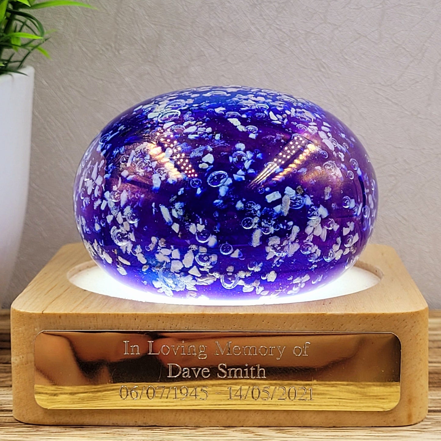 ashes in glass paperweight in iridescent blue sat on a illuminated light stand