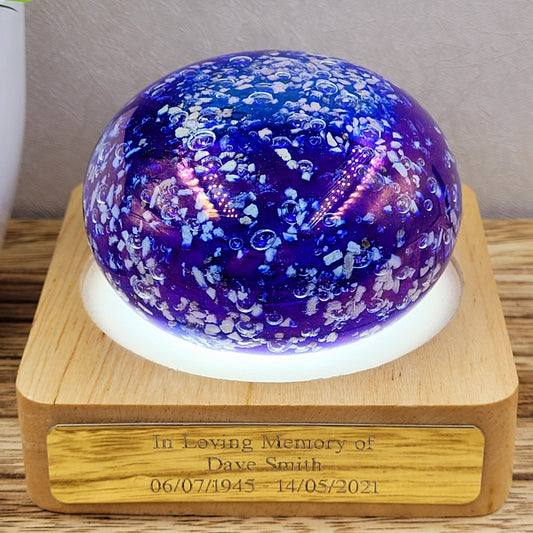 blue cremation ashes in glass paperweight ornament in iridescent blue